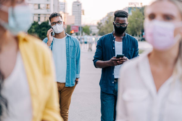 istock People with protective masks walking outdoors in the city. 1369536921