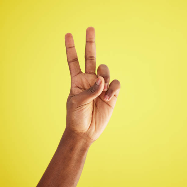 istock Studio shot of an unrecognisable man making a peace sign against a yellow background 1369539509