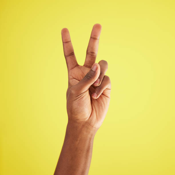 istock Studio shot of an unrecognisable man making a peace sign against a yellow background 1369539512