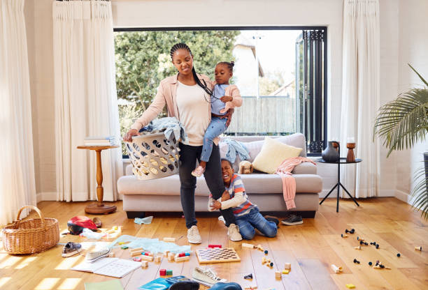 photo d’un petit garçon qui fait une crise de colère tout en tenant la jambe de sa mère à la maison - chaos photos et images de collection