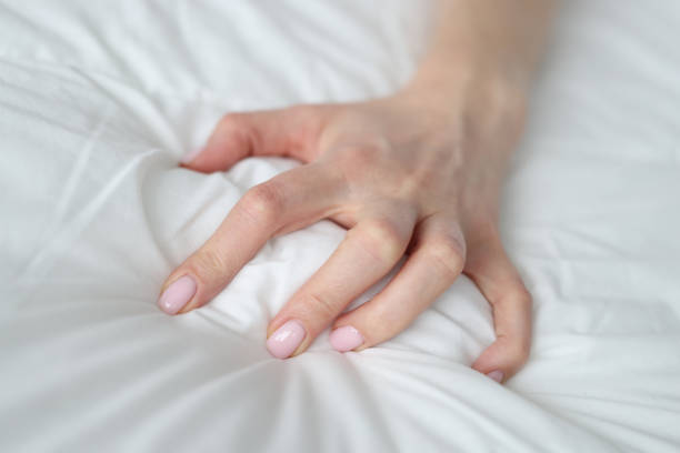 Woman hand squeezing white blanket at home closeup stock photo