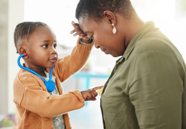 foto de una niña jugando al médico mientras escucha el pecho de su madre - disfrazar fotografías e imágenes de stock