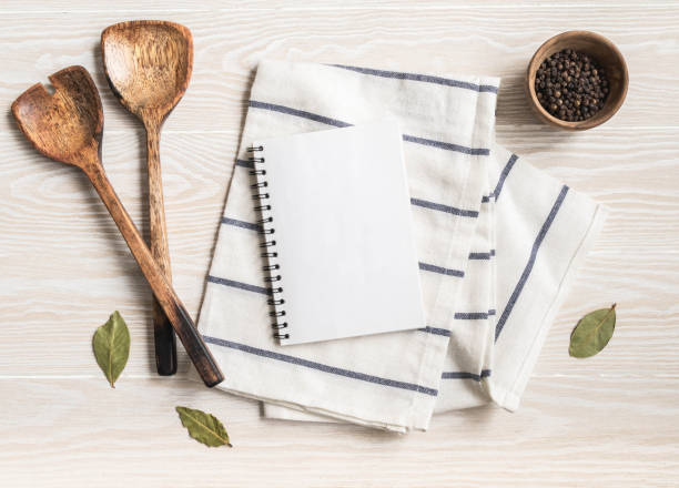 istock Minimal white kitchen background with blank notebook for text, cotton napkin, various spices and wood appliances. 1369542180