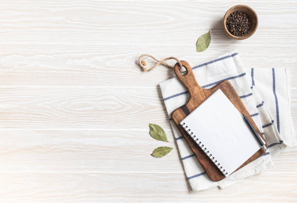 istock Minimal white kitchen background with blank notebook for text, cutting board, cotton napkin and various spices 1369542181