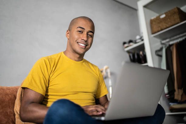istock Portrait of a young man using laptop at home 1369545436
