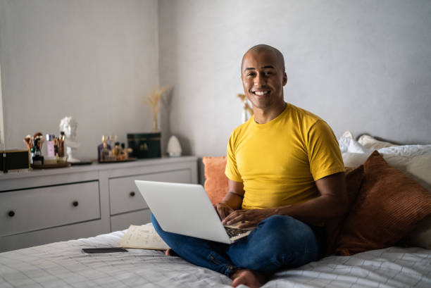 istock Portrait of a young man using laptop at home 1369545444