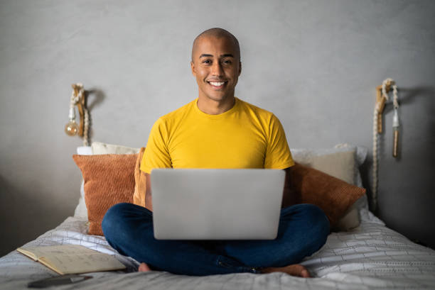 istock Portrait of a young man using laptop at home 1369545448