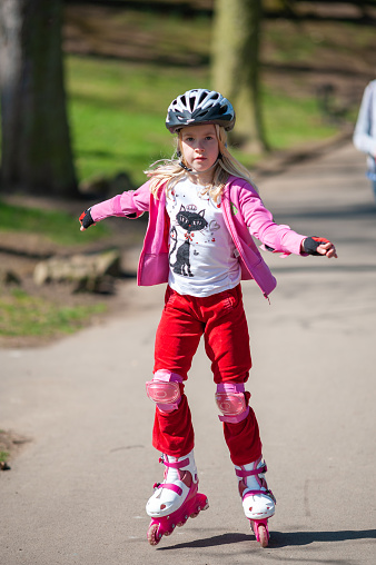 A young girl on roller blades wearing protective equipment