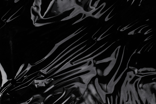 Textura de envoltura de plástico arrugado sobre un fondo negro. Fondo de pantalla del paquete photo