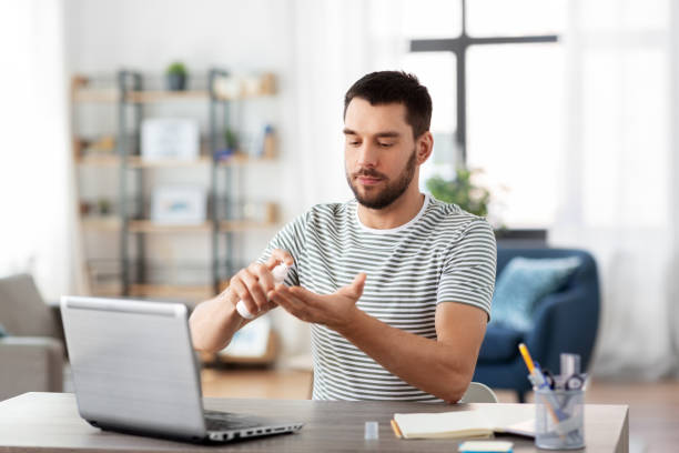 istock man using hand sanitizer at home office 1369553466