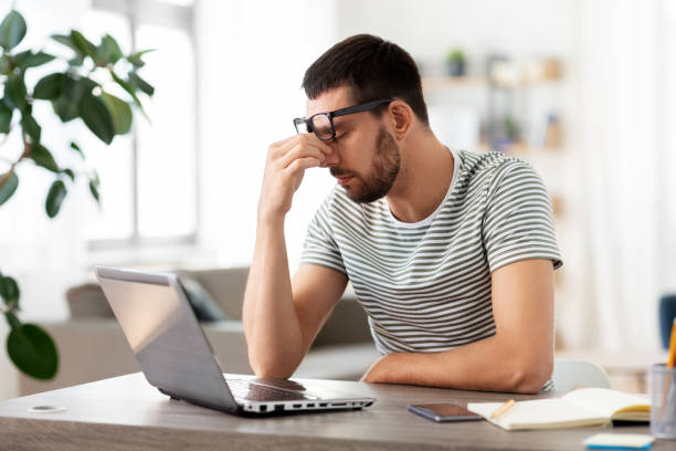 istock tired man with laptop working at home office 1369554791