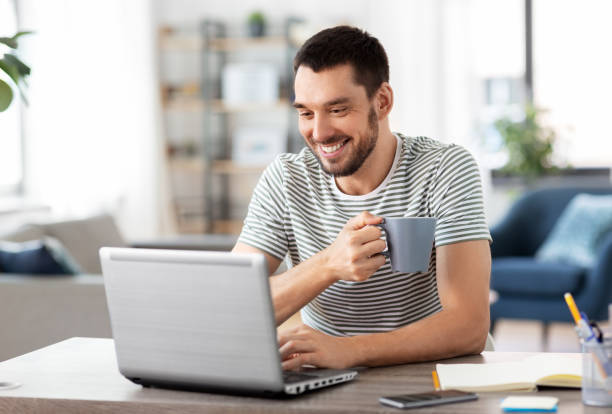 istock man with laptop drinking coffee at home office 1369554803