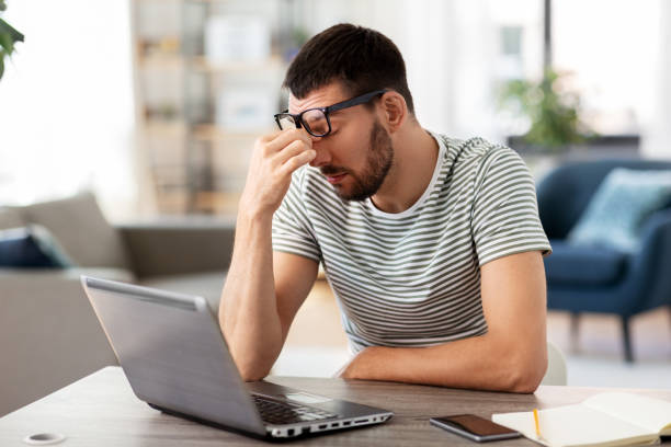 istock tired man with laptop working at home office 1369554822