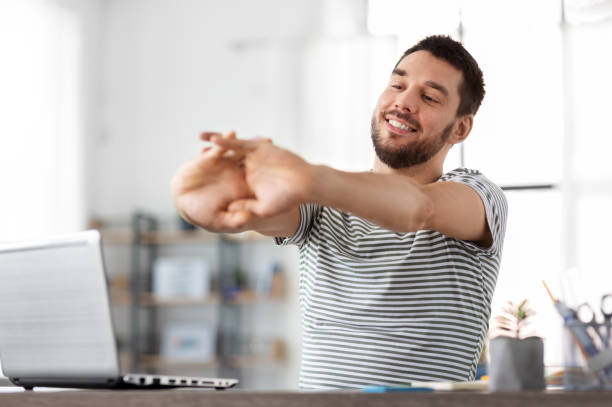 istock happy man with laptop stretching at home office 1369555588