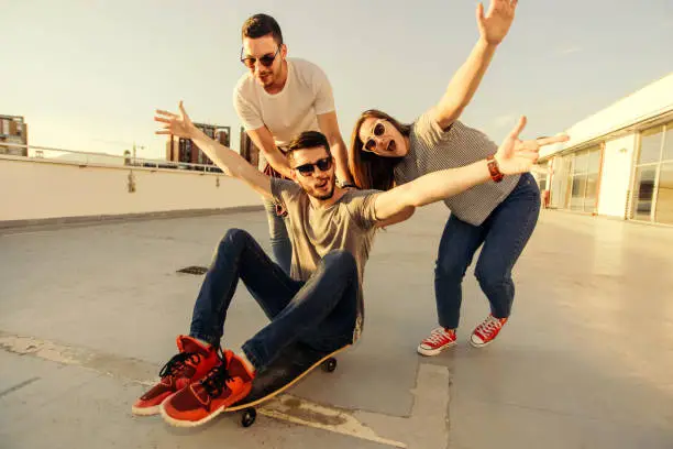 Group of friends having fun with longboard at sunset on rooftop