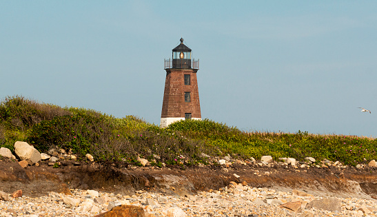 The Point Judith Lighthouse above sand dunes and beach grass brush in Narragansett Rhode Island.