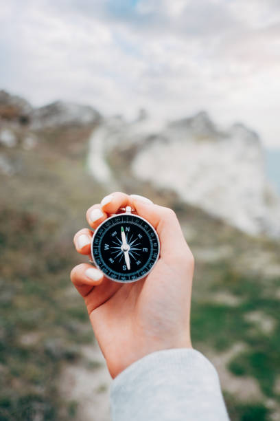 istock Navigational compass in a hand outdoor. 1369557078