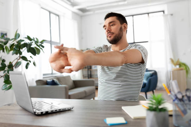 istock man with laptop stretching at home office 1369557178