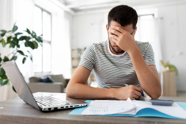 istock man with papers and laptop working at home office 1369558115