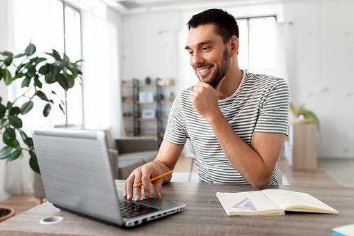 technology, remote job and business concept - man with laptop computer working at home office