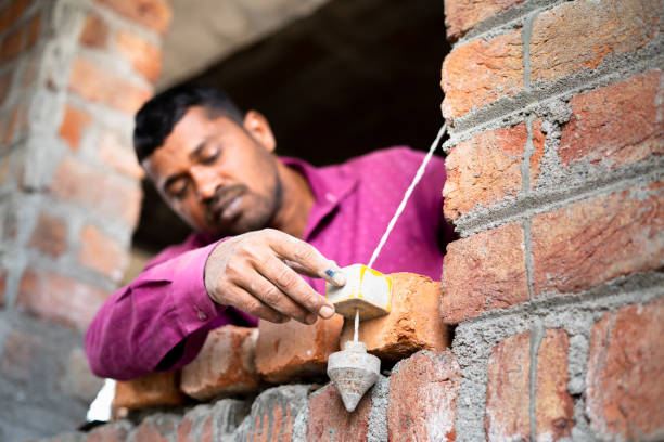 istock Focus on hand, Construction labour checking level of wall using plumb bob vertical measuring tool at site - concept of professional skilled daily wager and renovation 1369559563