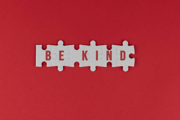 istock Be kind. Kindness concept with text on white puzzle jigsaw on red background. 1369559766