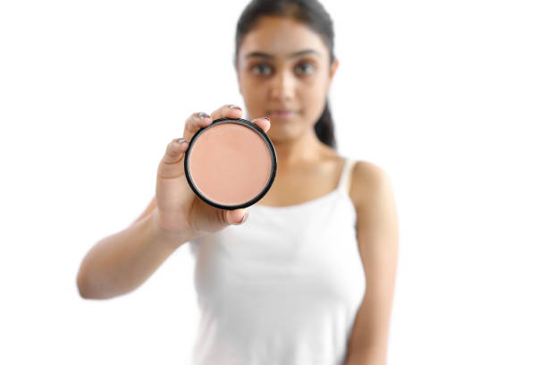 Beautiful young woman showing moisturizer by holding it in hand.