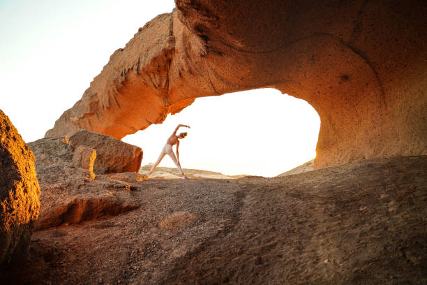 Woman practicing yoga. Back view. Healthy morning routine. Rocky landscape. A lot of copy space.
