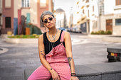 istock Young modern fashionable girl with short hair wearing sunglasses and a lot of jewelry. City street style. 1369560034