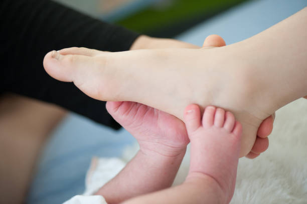 生まれたばかりの赤ちゃんの足.ハッピーファミリー、お母さんとお父さんは赤ちゃんの足を抱きしめる。 - hands and feet flash ストックフォトと画像