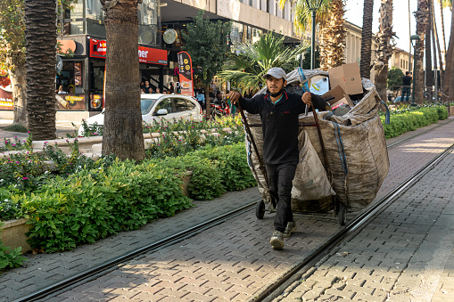 Antalya, Turkey - November 15, 2021: garbageman with a huge garbage bag on the city street