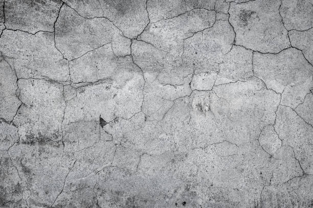 istock Gray cracked stucco, concrete and cement wall pattern. Asymmetric and abstract broken on textured Background. 1369564667