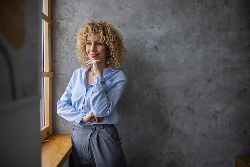 Portrait of confident Caucasian businesswoman, looking through window office