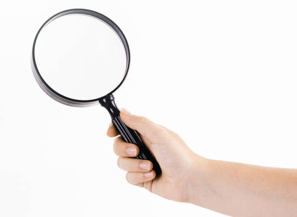 istock Woman's hand holding a large magnifying glass on white background with copy space 1369568774