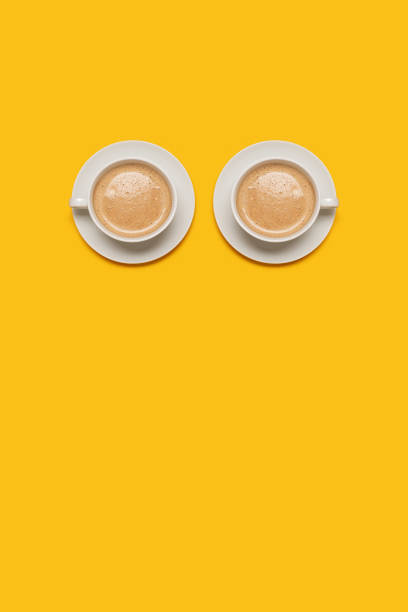 istock Two cups of coffee forming eyes on a yellow background 1369569751