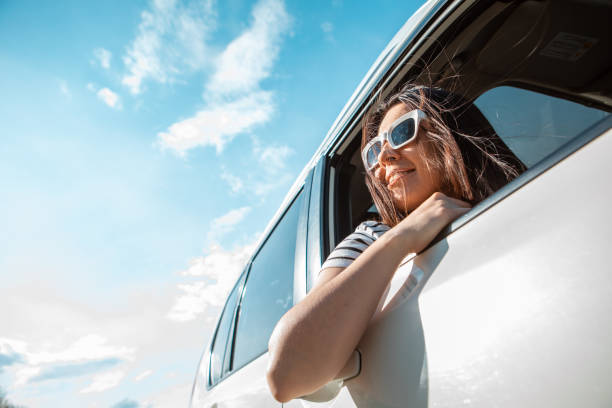 woman looking out from car window. road trip stock photo