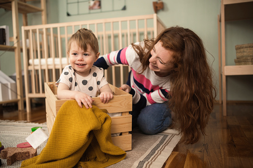 Young mother playing with her baby girl in the box