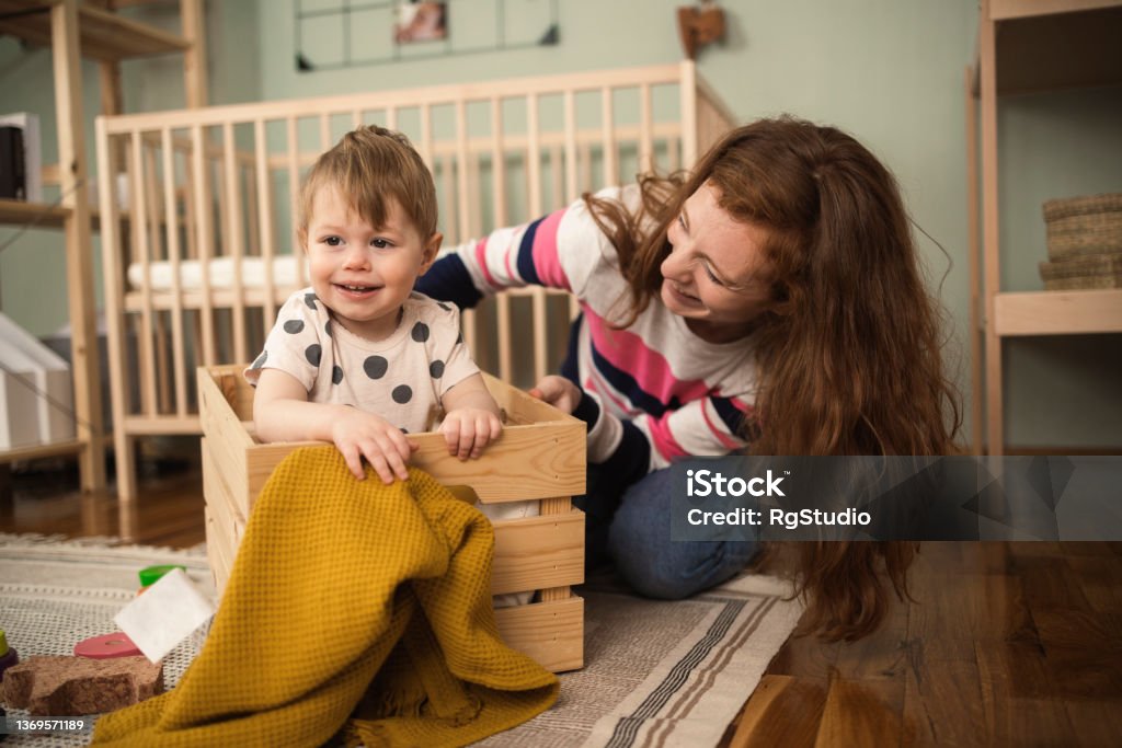 Young woman playing with her cute baby in the box Young mother playing with her baby girl in the box Small Stock Photo