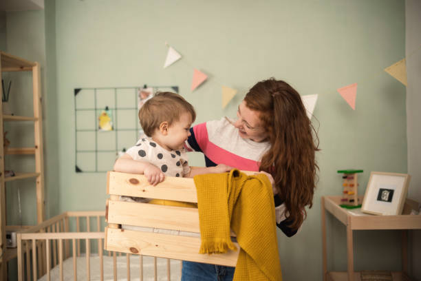 istock Young woman holding a box with her cute baby inside 1369571200