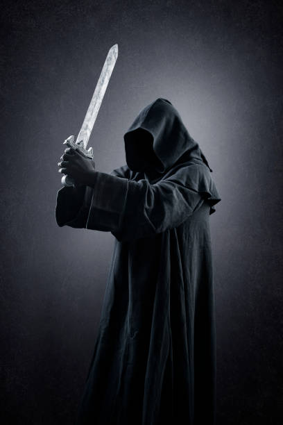 istock Warrior with hooded cape and medieval sword over dark misty background 1369572421
