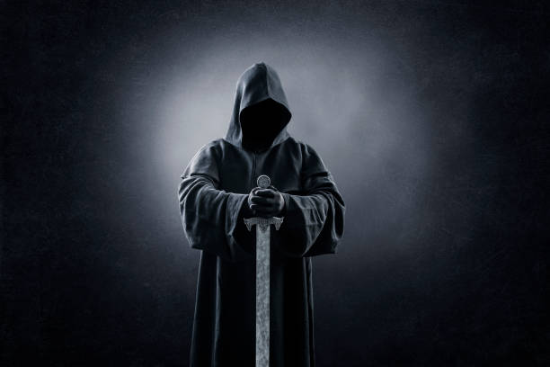 istock Warrior with hooded cape and medieval sword over dark misty background 1369572424