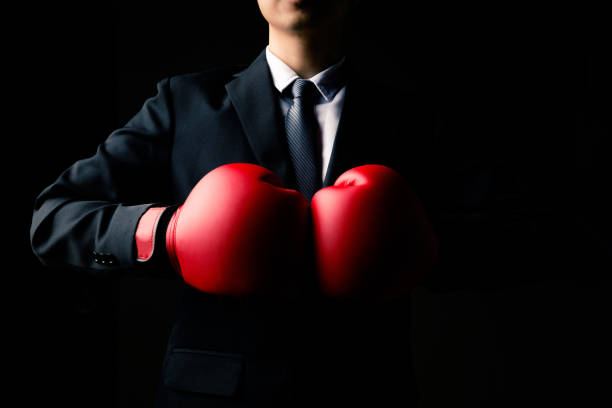 Businessman in boxing gloves standing on black background. stock photo