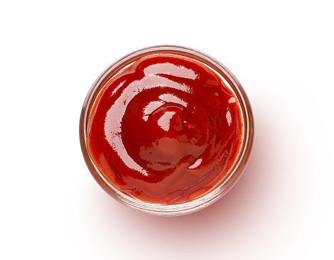 Red tomato sauce in glass bowl isolated on white background with clipping path. Top view. Flat lay.