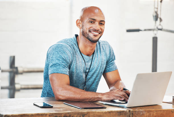 istock Portrait of a muscular young man using a laptop while working in a gym 1369575081