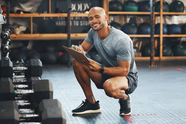 Portrait of a muscular young man using a clipboard while checking equipment in a gym Gotta make sure it's all here for you to make gains gym men africa muscular build stock pictures, royalty-free photos & images