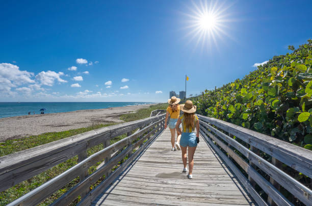 istock Women walking on boardwalk on beautiful Florida beach. 1369575526