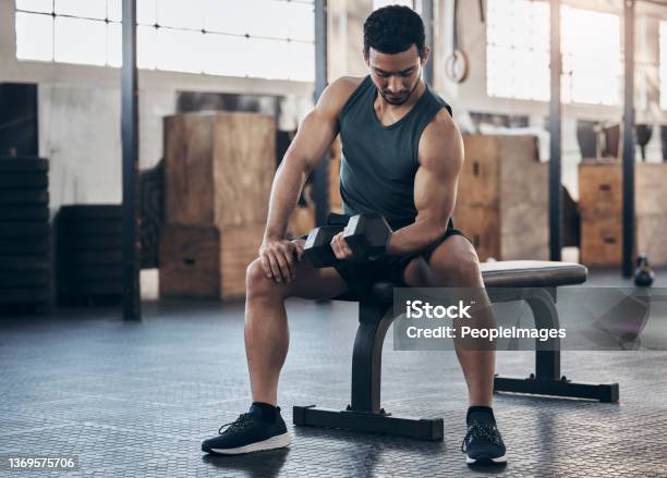 Shot Of A Muscular Young Man Exercising With A Dumbbell In A Gym Stock Photo - Download Image Now