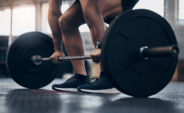 primer plano de un hombre irreconocible haciendo ejercicio con una barra en un gimnasio - levantamiento de pesas fotografías e imágenes de stock