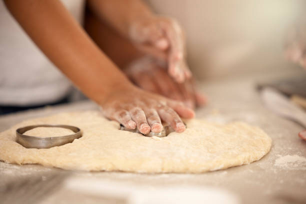 istock Cropped shot of an unrecognizable girl using a cookie cutter while making cookies at home 1369576584