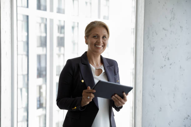 istock Happy successful middle aged businesswoman holding tablet 1369578692